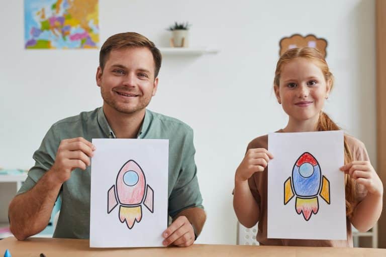 Father and Daughter Holding Pictures of Space Rockets