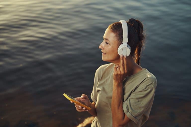 Female pressing headphones closer while enjoying music in nature